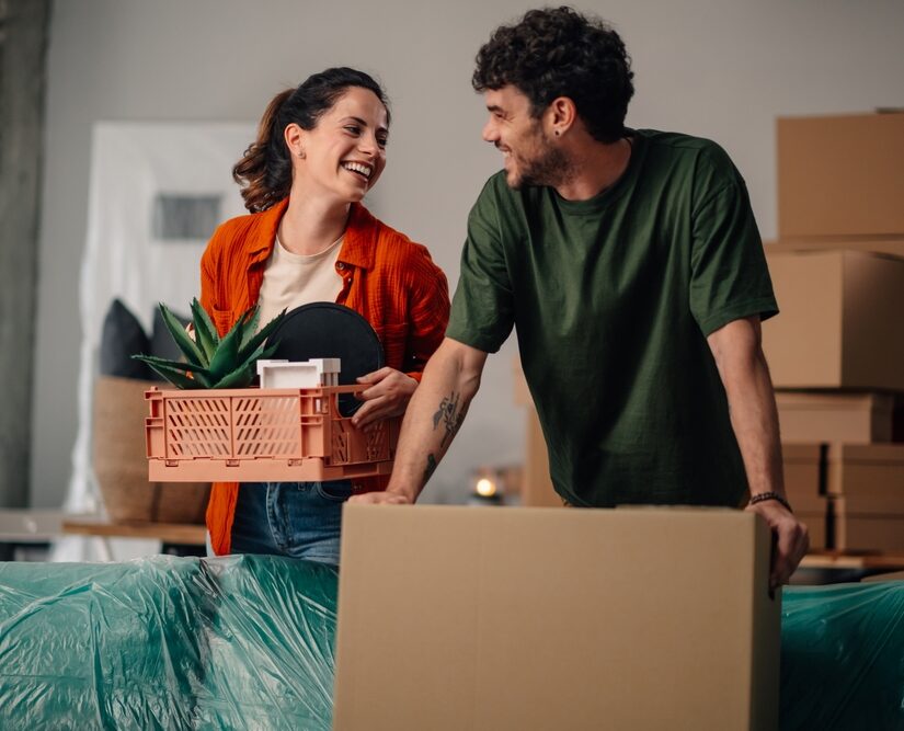 Young,Couple,Moving,Into,Their,New,Apartment,,Joyfully,Carrying,Boxes
